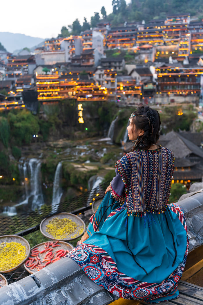 Mujer sentada viendo el paisaje lijiang